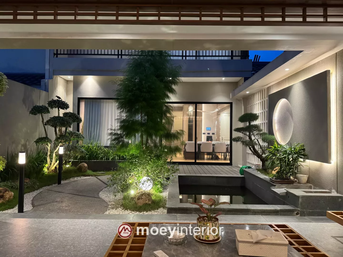 Detail taman belakang dengan pohon cemara dan pencahayaan uplighting